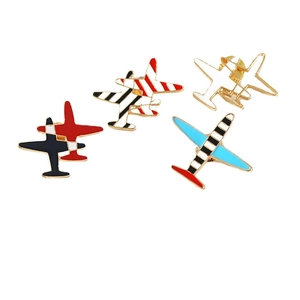 Lot de quatre pin's émaillés en forme d'avion coloré avec finition dorée sur blanc