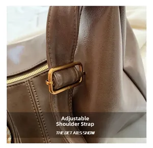 Detail view of adjustable brown leather shoulder strap with a gold square metal buckle