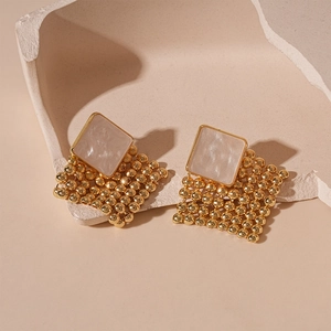 Detail of gold woven diamond earrings with white resin inlay and beaded mesh texture