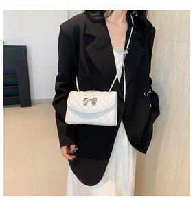 Détail du sac à main matelassé blanc avec boucle nœud argentée et bandoulière