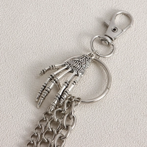 Macro shot of silver metal skeleton hand keychain with fine carving and spring buckle
