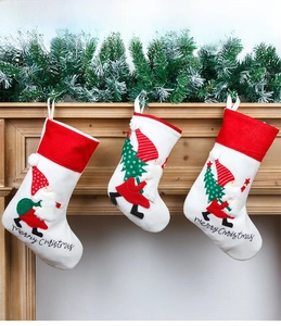 Three Nordic embroidered white Christmas stockings hanging on a wooden fireplace mantle