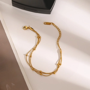 Detail of a triple-layered gold stainless steel beaded snake chain bracelet with lobster clasp