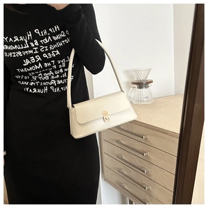 Close-up of a white vintage PU leather baguette bag with elegant gold metal clasp detail