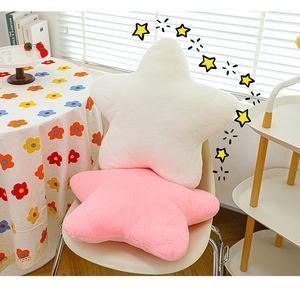 Detail showing soft white and pink star plush pillows in a cozy home setting