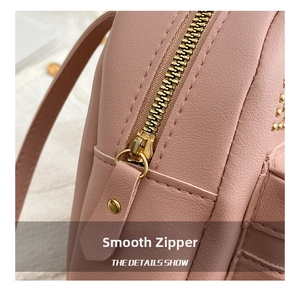 Detail of smooth gold zipper and pebble leather texture on pink studded backpack
