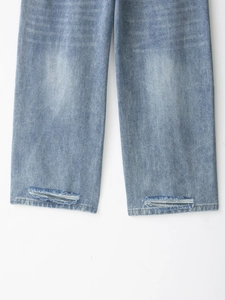 Dettaglio ravvicinato dell'orlo dei jeans blu chiaro con strappi e trame sfilacciate