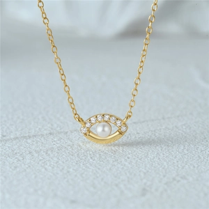 Macro detail of gold S925 silver necklace featuring a pearl devil eye pendant with crystals