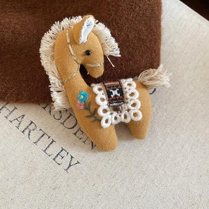 Close-up of handmade fabric horse brooch with mustard yellow texture and embroidery