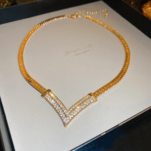 Detailed close-up of a gold-plated V-shaped necklace pendant with sparkling cubic zirconia