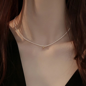 Minimalist freshwater pearl choker necklace with a gold bead pendant on a female model
