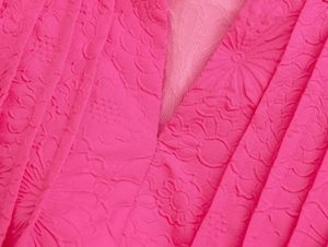 Macro shot of pink mini dress featuring floral embossing and V-neck with ruffle detail