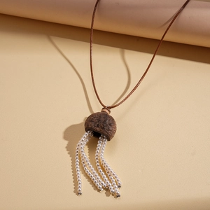Détail du collier à pompons bohème avec pendentif en coque naturelle et perles