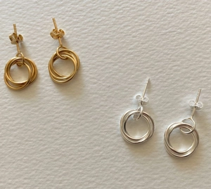 Close-up of interlocking triple hoop earrings in polished gold and silver finishes