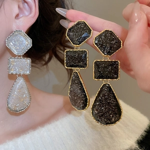 Detail of geometric resin drop earrings in black gold and white silver finishes