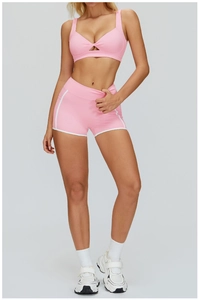 Dettaglio del set da yoga rosa con reggiseno incrociato e pantaloncini sportivi coordinati