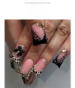 Detail of Y2K duckbill nails with leopard print, black bows, and sparkling rhinestones