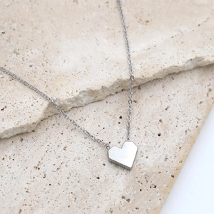 Minimalist 18k titanium steel necklace featuring a red acrylic heart pendant on a stone
