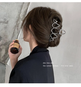 Close-up of silver metal shark hair claw clip with wavy lines on model bun hair