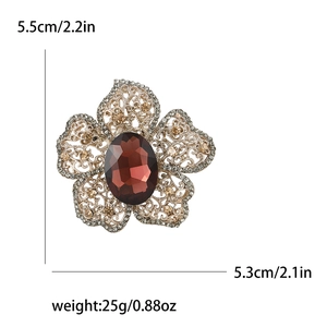 Broche fleur dorée vintage avec pierre marron et strass sur fond blanc épuré