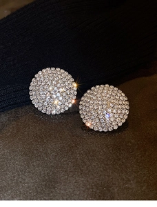 Macro shot of silver round stud earrings with sparkling pavé crystals and starburst effect