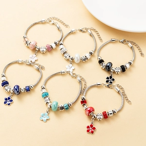 Detailed view of colorful beaded charm bracelets with silver snake chains and flower pendants