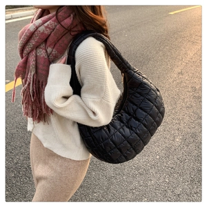 Chic black quilted nylon crescent bag worn on shoulder by model in golden hour street shot