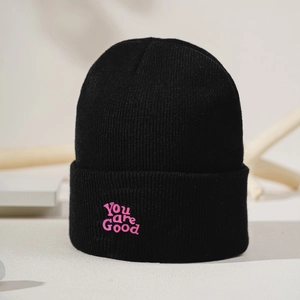 Close-up of pink YOU ARE GOOD embroidery on a high-density black knitted beanie