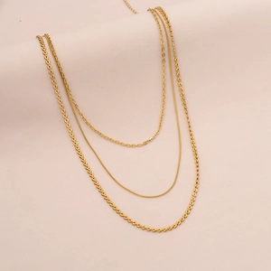 Detail of gold triple-layer necklace featuring heart-shaped links and sleek snake chain