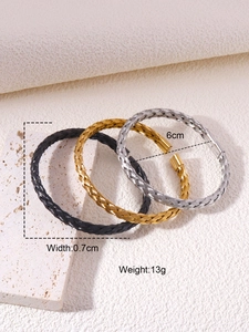 Macro detail of braided twist cuff bracelets in black, gold, and silver stainless steel