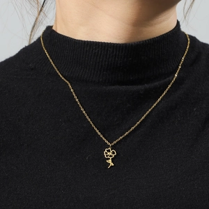 Close-up of a gold floral pendant necklace worn on a black knit sweater background
