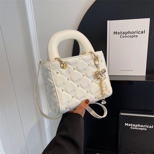 White quilted crossbody bag with gold floral rivets and pearl bow charm accessory