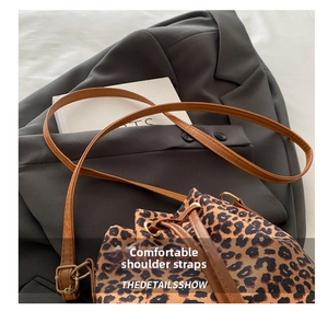 Close-up of leopard print bucket bag with brown leather strap and gold drawstring eyelets