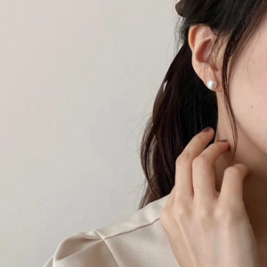 Close-up of elegant round pearl stud earring on earlobe for a minimalist style