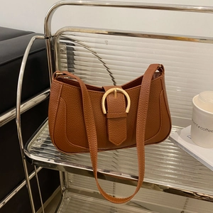 Macro view of brown lychee grain leather underarm bag with gold D-buckle detail