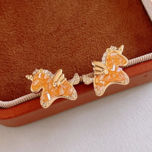 Macro detail of unicorn stud earrings with orange resin and gold-plated rhinestone finish
