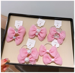Detail of pink bow hair clips with pearls and crown gems for girls hair styling