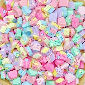 Macro shot of mini house-shaped resin charms in pastel macaron colors with letter prints