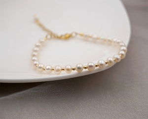 Detail of freshwater pearl bracelet with gold beads on white plate and mesh