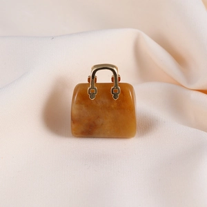 Detailed macro view of a yellow jade handbag pendant with a golden handle and natural texture