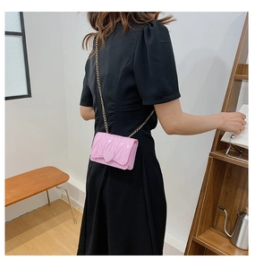 Pink heart-buckle jelly crossbody bag with gold chain strap worn by a young girl