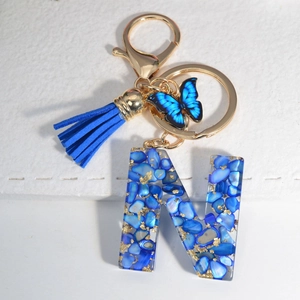 Macro shot of resin letter N keychain with blue stones, gold foil and blue tassel