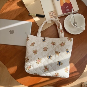 Quilted tote bag with cute bear patterns displayed on a wooden table with accessories