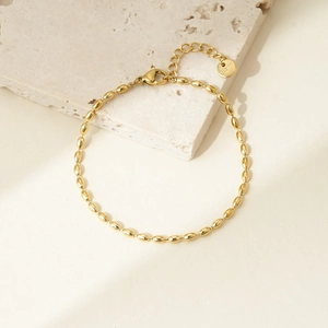 Detailed shot of a gold-plated oval bead bracelet with a 316L stainless steel logo tag