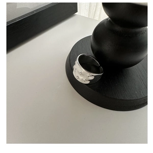 Detail view of the S925 sterling silver star ring with embossed patterns on black wood