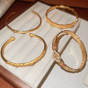 Macro view of four vintage gold bracelets featuring matte, embossed and filigree details
