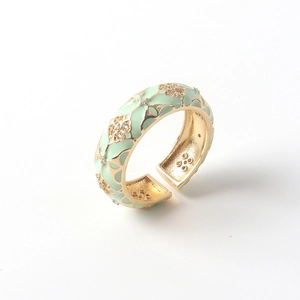 Detail of 18K gold ring with light green enamel floral pattern and small zircons
