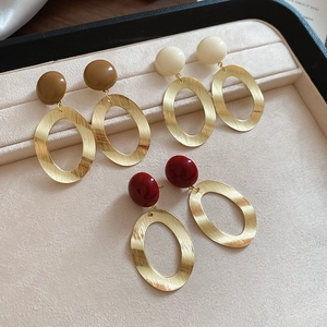 Detail view of retro oval brushed metal earrings with resin studs in brown and burgundy colors