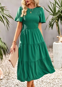 Detail of green round-neck dress with smocked waist and tiered skirt on model