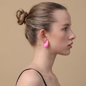 Professional shot of minimalist pink teardrop stud earrings worn by a model on plain background